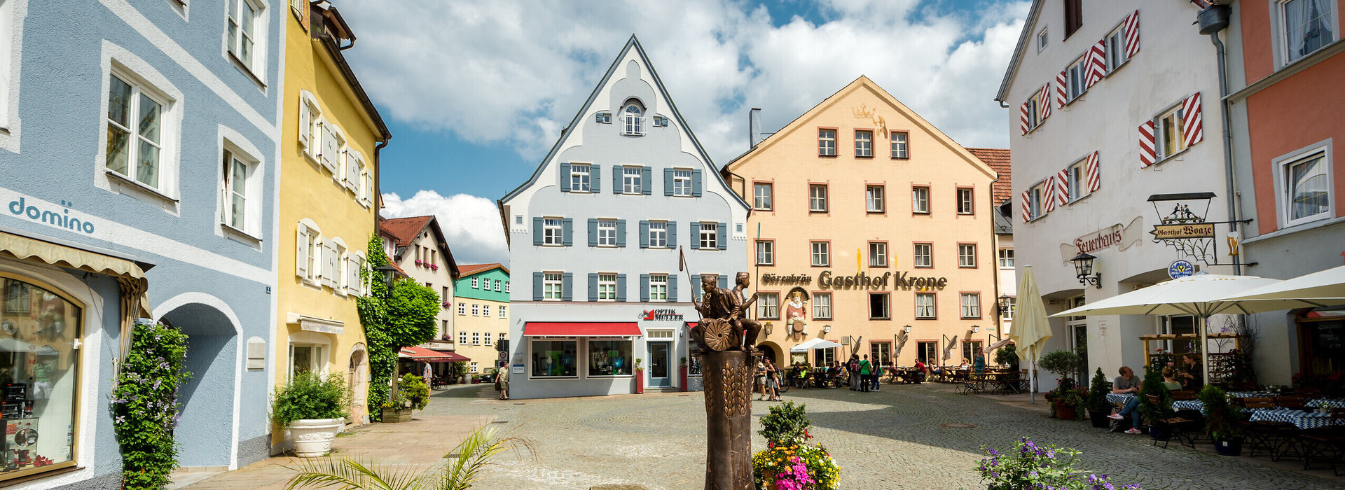 Der Schrannenplatz in Füssen mit historischen Gebäuden und Blumenkästen. Ein idyllischer Ort im Herzen der Stadt.