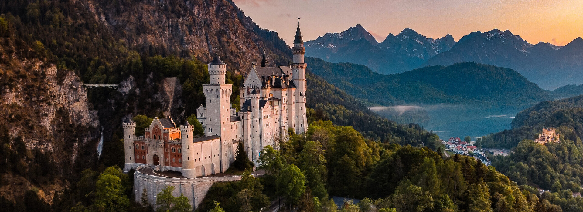 Panoramablick auf das Märchenschloss Neuschwanstein inmitten grüner Berge. Ein magischer Ort in Bayern.