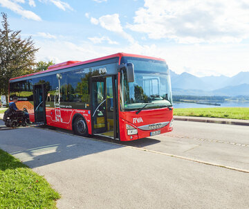 Foto eines Nahverkehrs-Busses mit dem Forggensee und den Ammergauer Alpen im Hintergrund