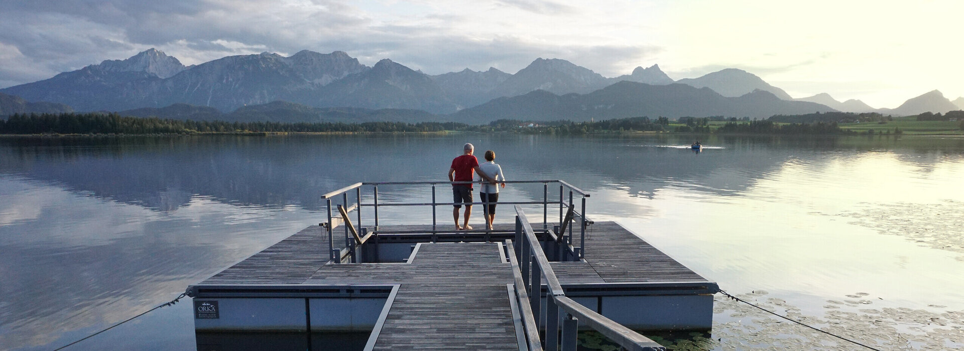 Das Bild zeigt einen großen Steg, der in den Hopfensee ragt. Am Ende des Stegs wird öffnet sich eine Plattform, in deren Mitte ein Kneipptretbecken eingelassen ist. 